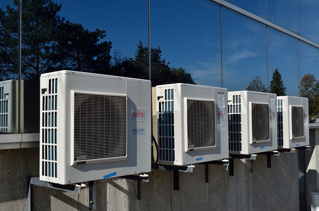 Alignement de plusieurs bloc de climatisation devant une facade vitrée d'habitation ou de bureau.